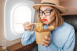 © EdNurg - disgruntled passenger in business class tries and sniffs spoiled food on the plane. The concept of changes in the sense of smell and taste buds and poor service in the airline