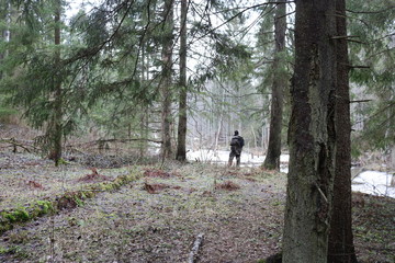 Forest spring landscape with the figure of a man standing on the Bank of a frozen river.