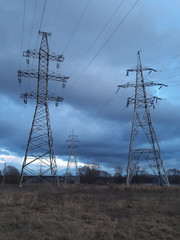 Metal transmission tower on a background of anxiety cloudy sky on the outskirts of the city. High voltage towers. Desolate landscape. Apocalypse concept