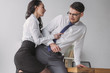 passionate secretary holding tie and embracing scared businessman while seducing him in office