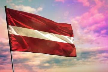 Fluttering Latvia flag on colorful cloudy sky background. Prosperity concept.