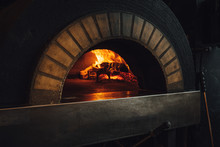 Dark Brick Pizza Oven With Fire In Restaurant