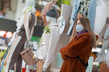 Young Asian Girl In A Medical Mask Next To Mannequins In A Store