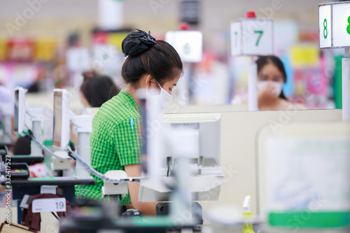 Cuadros en Lienzo Cashier or supermarket staff in medical protective mask working at supermarket