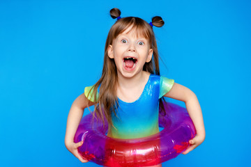 little cute girl child in a swimsuit with a swimming circle on a blue background