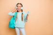 © deagreez - Photo of pretty funny little lady listen earphones youth modern song walk school browsing telephone wear teal bag blue pullover jeans isolated beige pastel color background