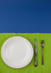 Empty plate with fork and knife on blue table. Table arrangement.