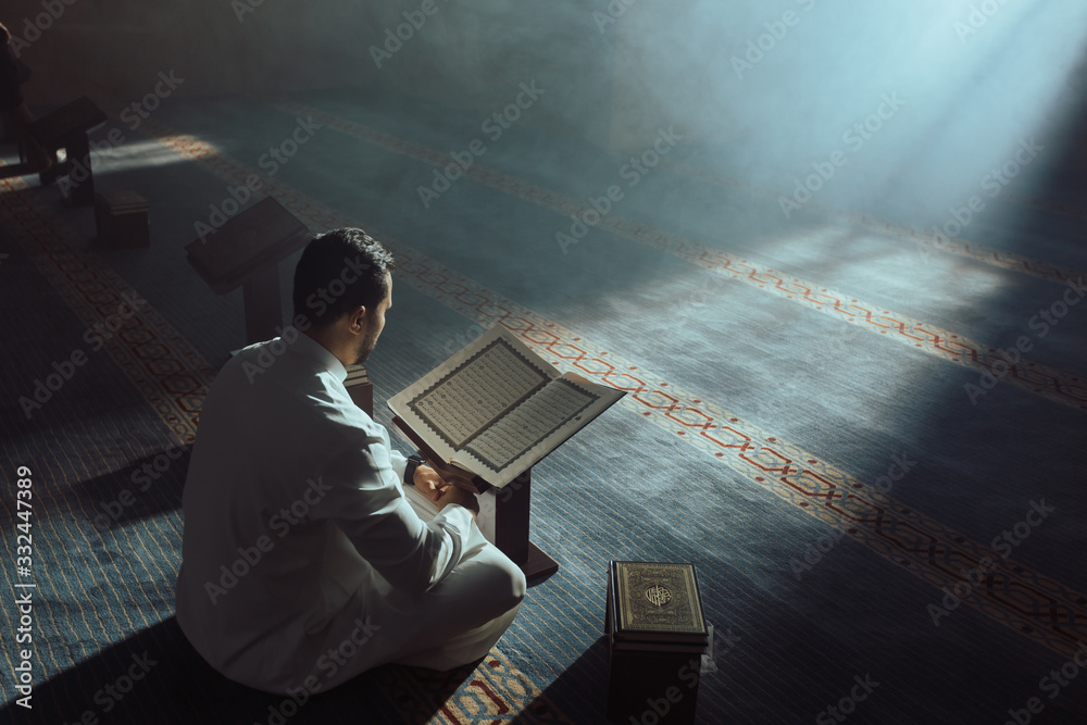 пожилой арабский мужчина читает Коран, рядом стоит молодой человек