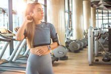Beautiful young woman in sportswear with airpods listening to music in gym