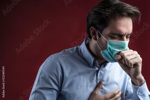 Single sick male standing on background with medical mask and coughing in his hand, studio shoot