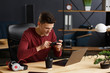 © YURII MASLAK - Young man playing games on mobile phone in home office with laptop. Relaxation, taking a break. Young people working with mobile devices.