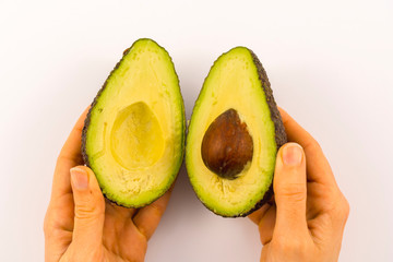 Hands of a woman separating the avocado in two. Recipe to prepare a nice guacamole