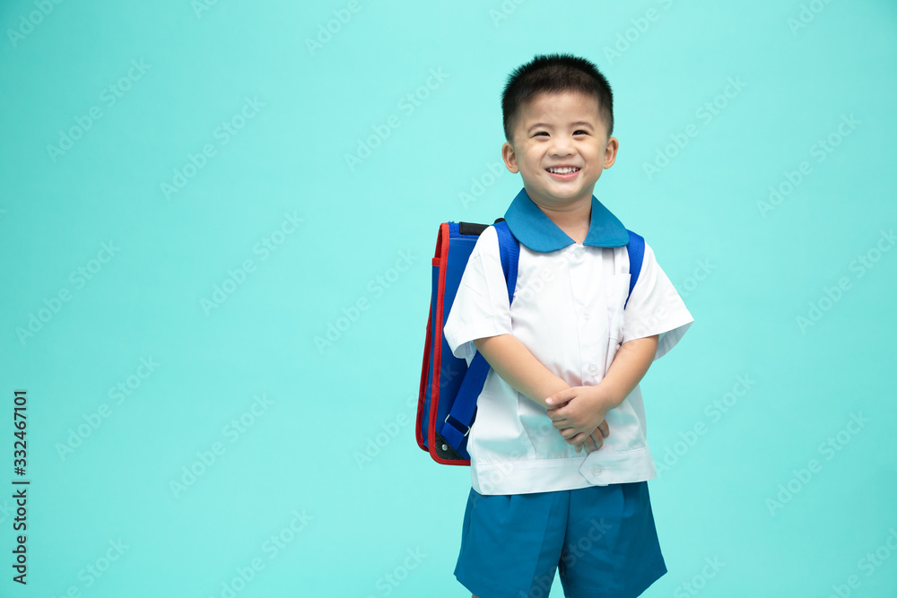 Cheerful smiling asian little boy in a school uniform with backpack having fun isolated on green background, First day of kindergarten and Back to School concept - obrazy, fototapety, plakaty 