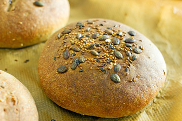 Cereal bread sprinkled with sesame seeds on top on parchment paper. Background about homemade bread, a loaf of whole grain bread