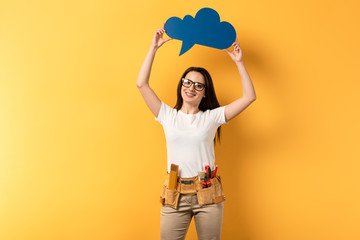 Wall Mural - smiling repairwoman holding blue thought bubble on yellow background