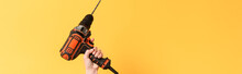 Panoramic Shot Of Woman Holding Drill On Yellow Background