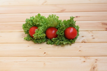 red tomatoes and green salad on a wooden background