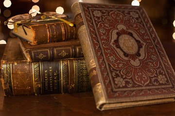 Wall Mural - A vintage pile of three old brown leather books with eye glasses on a wood table.