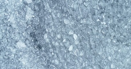 Wall Mural -  Aerial top view of cracked ice. Drone shot flying up over melting ice, global warming, climate change background. Beautiful winter bright pattern.