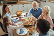© Drazen - Happy multi-generation family having lunch and toasting at dining table.