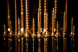Arranged group of shiny golden screws with mirroring itself and black background.