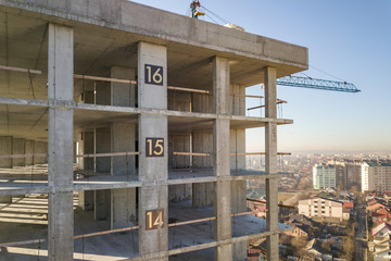 Aerial view of concrete frame of tall apartment building under construction in a city.