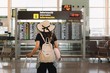 © Gabriel Trujillo/ADDICTIVE STOCK - Back view of woman in hat with suitcase and pillow looking at schedule in airport