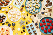 © Peter Karasev/ADDICTIVE STOCK - Top view of Christmas baubles and snowflakes placed near plates with various sweet pastry on yellow background