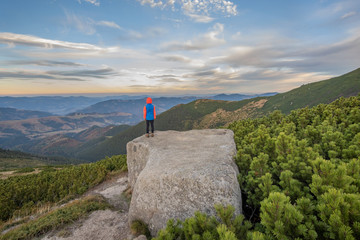 Wall Mural - Young child boy hiker standing in mountains enjoying view of amazing mountain landscape.