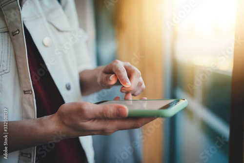 Fotografía Closeup of female hands using modern smartphone device browsing internet at sunn