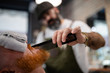 © Sergio Victor/ADDICTIVE STOCK - Blurred unrecognizable barber with comb fixing redhead man beard with towel covering eyes sitting in barbershop