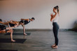 © JAKE JAKAB/ADDICTIVE STOCK - Slim barefoot female instructor in sportswear standing controlling group of sporty people concentrating and doing warrior pose three standing on sports mats in modern workout room