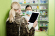 © phoenix021 - Customer  asking for medicine holding tablet in hands, pharmacist with surgical mask