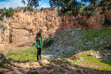 Rear view of a young woman standing on a mountain. A girl stands and looks at the mountain. A place for climbers at Crete island, Greece.