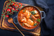 Traditional Brazilian fish stew moqueca baiana with fish filet in tomato sauce as top view in a modern design cast-iron roasting dish