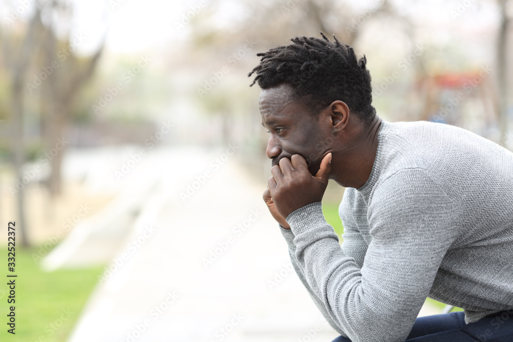 Pensive serious black man looking away on a park - obrazy, fototapety, plakaty 