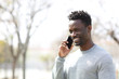 © PheelingsMedia - Happy black man talking on smart phone in a park