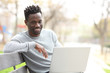© PheelingsMedia - Happy black man with laptop looking at camera
