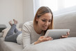 © makyzz - Woman using tablet on a home couch. Woman surfing on line or working from home concept