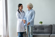 © fizkes - Happy caring young woman doctor or nurse and positive old lady with walking stick stand hugging talking, attentive caregiver support comfort optimistic senior grandmother give help and assistance