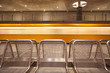 long-term exposure of a yellow through moving berlin subway in the station, in the demand a row of silver seats made of metal, in the background a facade of concrete, metro in motion
