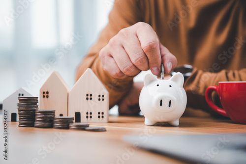Cuadros en Lienzo businessman hand holding coins putting in white piggy bank