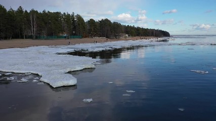 Wall Mural - Spring flight over the coastline with pieces of ice floating on the waves