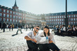 © eldarnurkovic - Visiting famous landmarks and places.Happy young couple tourists visiting famous Plaza Mayor square. Marid,Spain travel experience. Vacation in capital of Spain, blogger lifestyle.Europe honeymoon