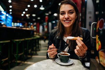 Woman eating deseert with chocolate.Craving for sweet and carbs.Breaking the diet.Happy tourist enoying traditional fried dough pastry desert churros with sugar dipped in hot chocolate saucein Spain.