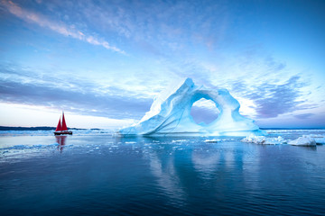 Wall Mural - sail boat with red sails cruising among ice bergs at dusk. disko bay, greenland.