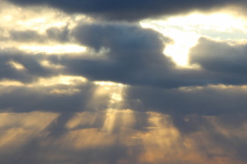 Wall Mural - the sun at sunset or dawn behind the clouds, shines through. the sun's rays in the sky