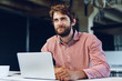 © fotofabrika - Portrait of young caucasian businessman using laptop computer at his workplace in modern office
