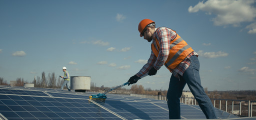 Technician cleaning solar panels on flat roof