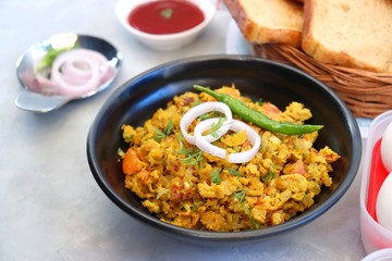 Wall Mural - Indian Breakfast Dish - Parsi Akuri or Anda Bhurji or Indian spicy scrambled eggs served with toasted brown bread & ketchup. Famous Indian street food. Ingredients background with copy space.